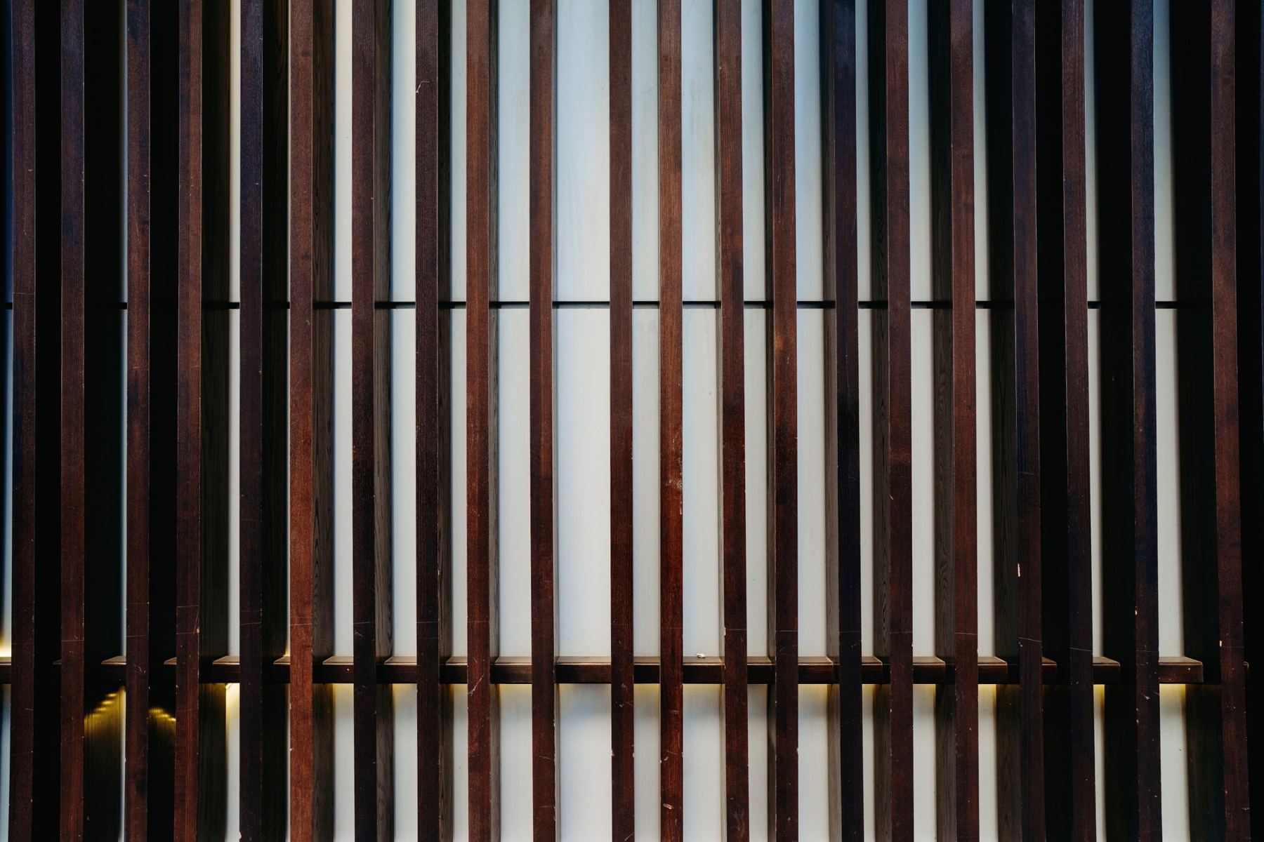Dark wooden slats in front of a softly lit panel.